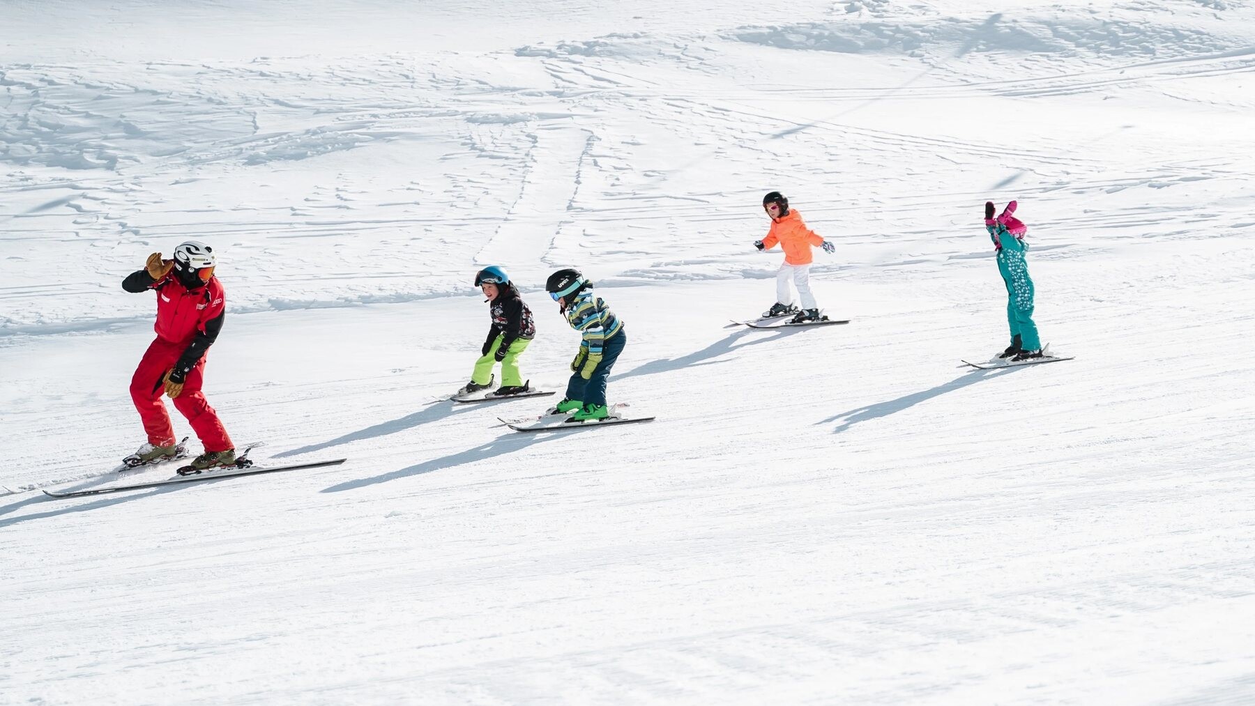 Skilehrer der Skischule Obergurgl führt vier Kinder über eine flache Piste