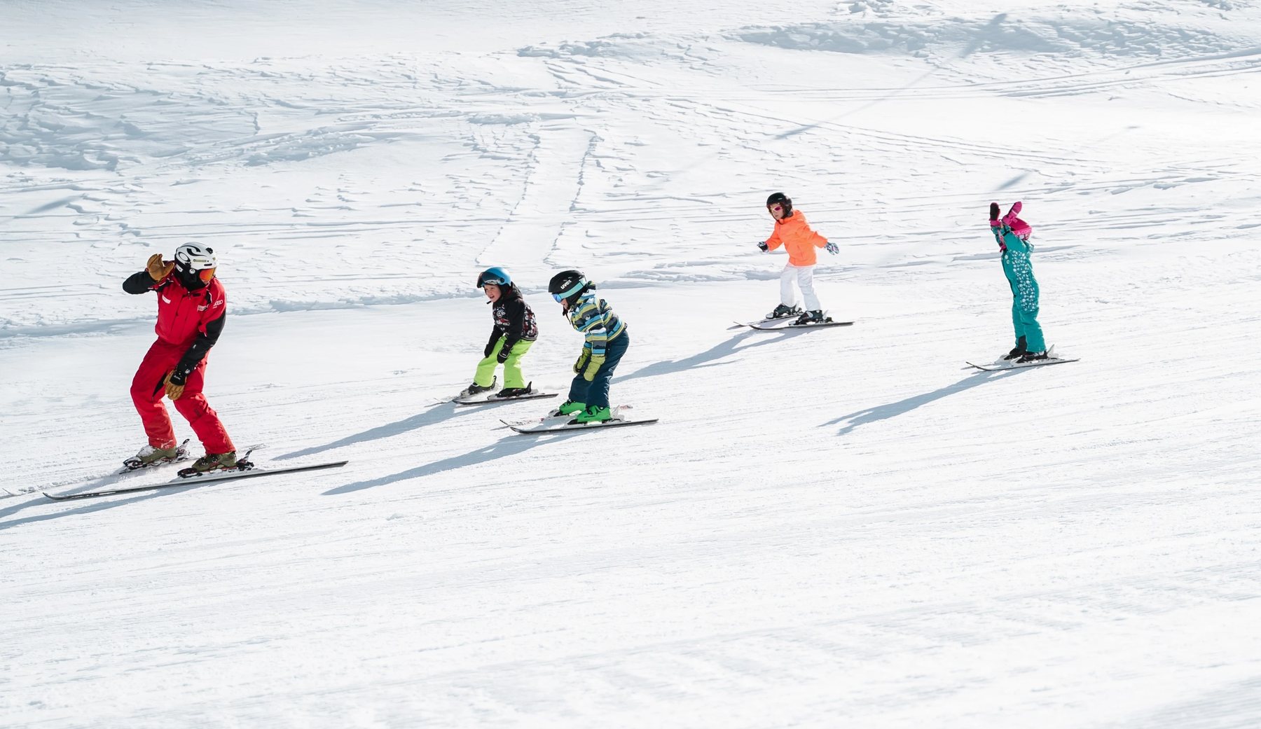 Obergurgl ski school instructor leading four children across a flat piste