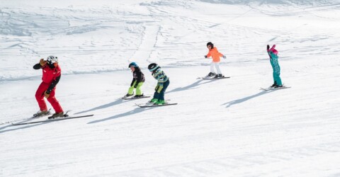 Obergurgl ski school instructor leading four children across a flat piste